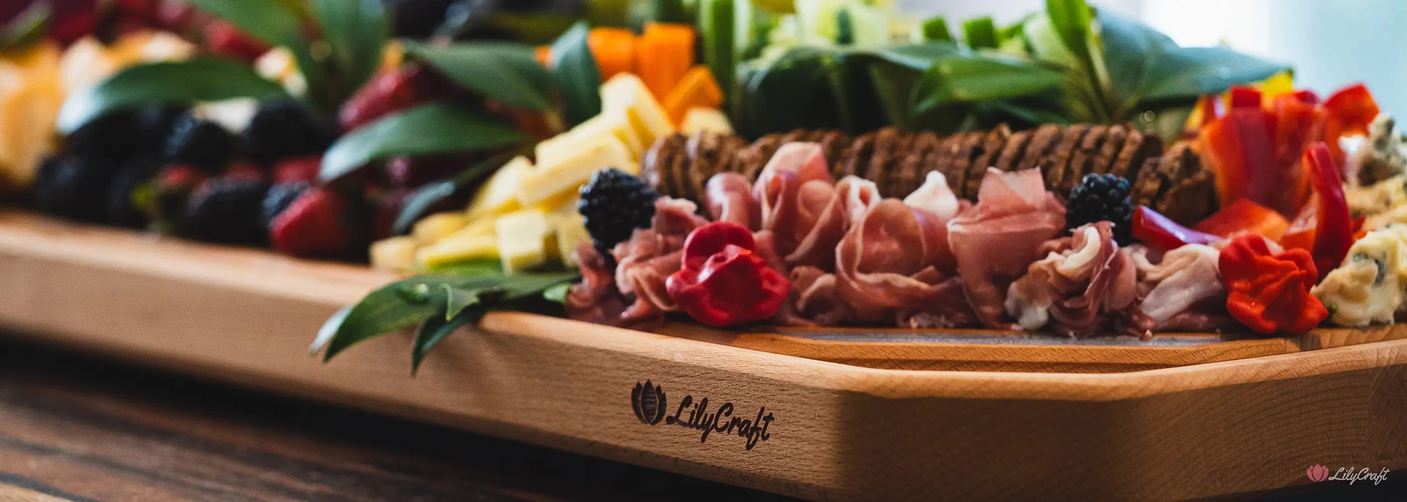 Wooden cutting board with a charcuterie board featuring meats, fruits, and vegetables on a wooden surface.