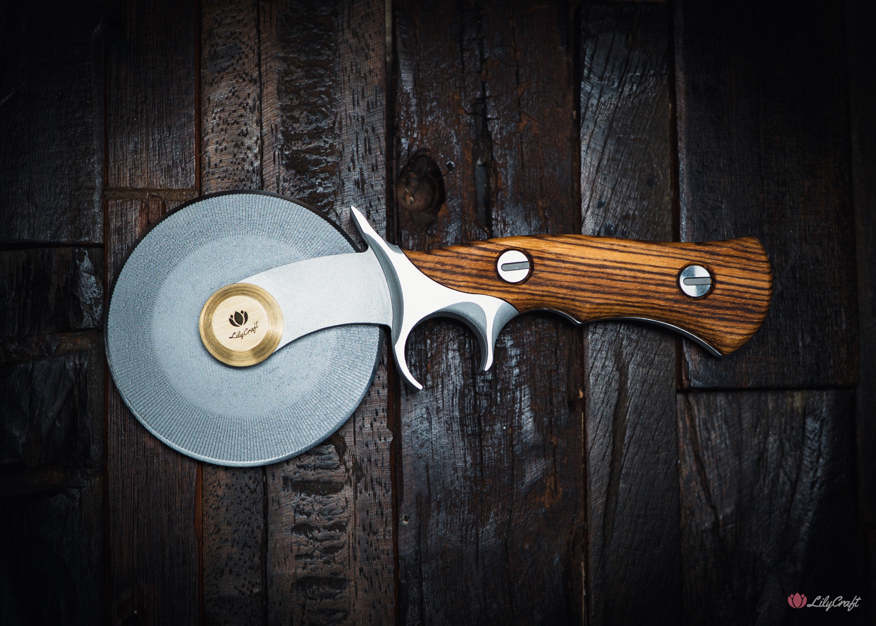 Pizza cutter with wooden handle and metallic blade on a dark wooden surface