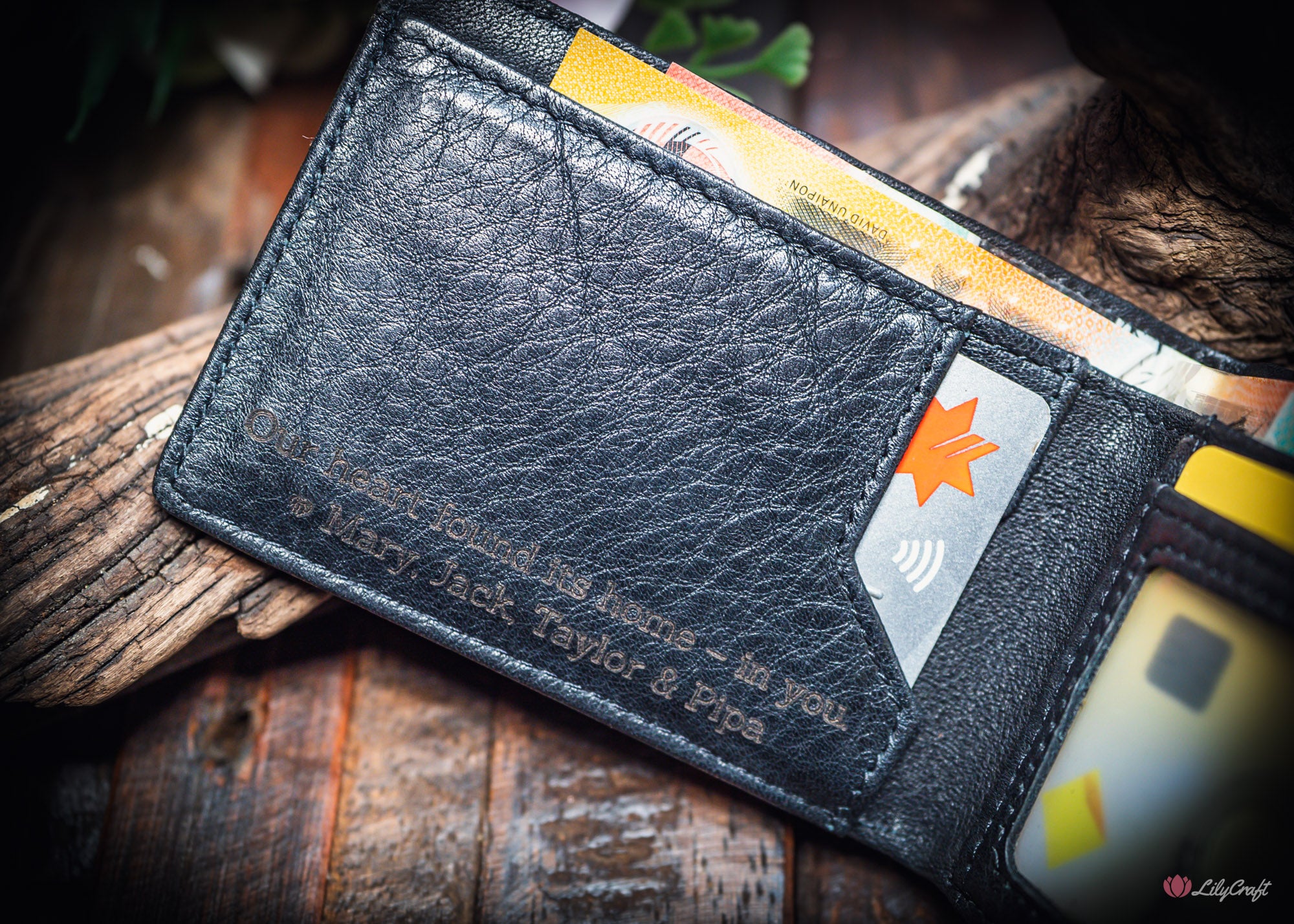 engraved black leather wallet for men on wooden surface