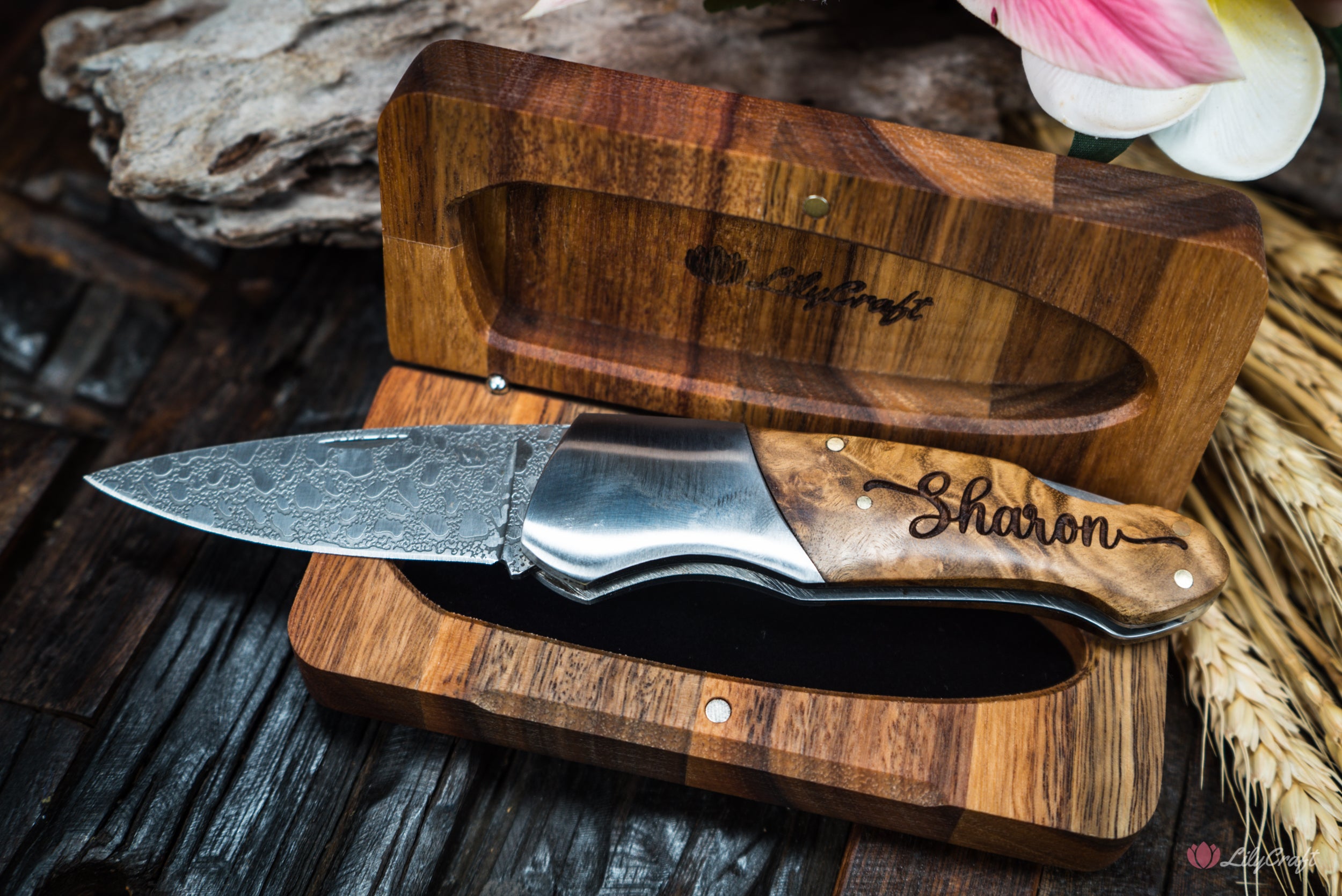 A folding knife with a birch wood burled handle and an intricately etched blade